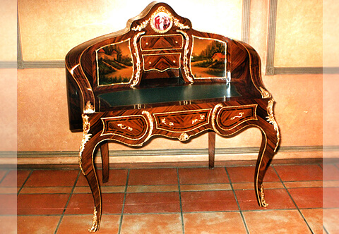 A French Louis XV and Vernis Martin style revival ormolu-mounted, sans traverse veneer inlaid and porcelain plate desk after the model by Theodore Millet circa 1880, The upper curved structure centered with a porcelain plate representing a court scene encircled with an ormolu border, surmounted and flanked with ormolu festoons, The superstructure is fitted with two doors to each side hand painted on the Vernis Martin style with outdoor scenes, with ormolu borders and pulls flanking two ormolu bordered drawers and one compartment, separated from the doors with two ormolu foliate pierced S shaped gadroons, The curved sides terminating with foliate ormolu clasps housing the gilt-tooled leather writing surface, above the serpentine shaped frieze with three drawers, The drawers are inlaid with sans traverse veneer inlays, ormolu border and foliate ormolu handles, the central drawers frieze with an ormolu shell, the two side drawers flanked with foliate C scroll ormolu gadroon, the frieze lower part contour of the desk is decorated with hammered ormolu filet extends to the internal side of the legs, The desk is raised on four cabriole legs ornate with fine ormolu acanthus chutes and pierced foliate ormolu turned acanthus sabots, The convex sides connected to the back and stunningly inlaid with sans traverse palisander veneer inlaid and cut veneer filet, The serpentine top ornamented with a foliate ormolu mount above a scalloped ormolu bordered part inset with a hand painting on the Vernis Martin style representing an outdoor nature scene, The lower section has a cut veneer medallion centered with a porcelain plate encircled in a foliate ormolu crowned border flanked with two faux drawers cut veneer sections decorated with two ormolu garlands