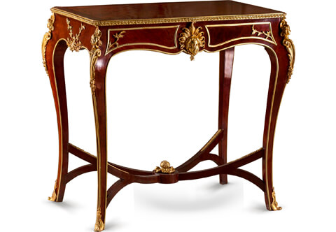 A Stately Belle Époque Louis XV Style Gilt-Ormolu Mounted veneer-inlaid Table De Salon on the manner of François Linke and ormolu mounts style by Léon Messagé, The table is raised by very elegant cabriole legs with acanthus shaped turned ormolu sabots and ormolu border that continues around the frieze and joined by an inverted curved double X stretcher adorned with a central ormolu leafy acorn in acanthus finial, At the top of each leg are exquisite and intricately chased ormolu chutes mounts of highly detailed busts of classical wigged maidens graced with scrolls and a feather headdress on a large beaded acanthus volutes and blossoming terminals, At the arbalest shaped frieze a central glamorous ormolu mount of a female face with elaborate leafy headdress amidst acanthus foliate patterns and a braided hair elongated and entwined under the chin. Flanked by ormolu panels imitating faux drawers cornered with thriving branch, The back is likewise, The sides are ornamented with a central ormolu mounts of blooming leafy branches, The crossbanded veneered molded top is surrounded with an impressive Cyma Recta design ormolu gallery